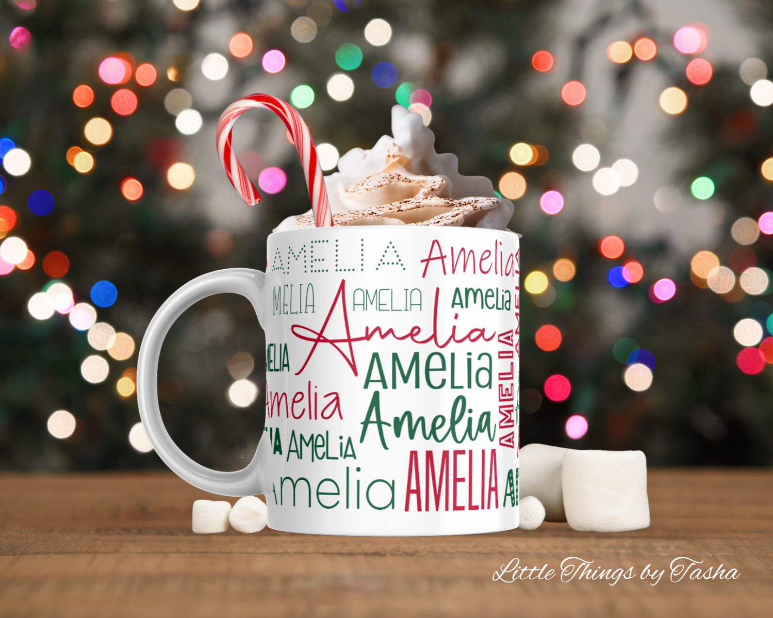 Personalized mug with whipped cream, candy cane, and 'Amelia' text against a blurred Christmas lights background.
