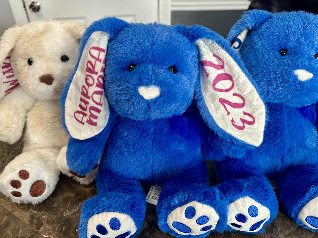 Blue plush elephant with 'Aurora' and '2023' on ears, next to a beige teddy bear.