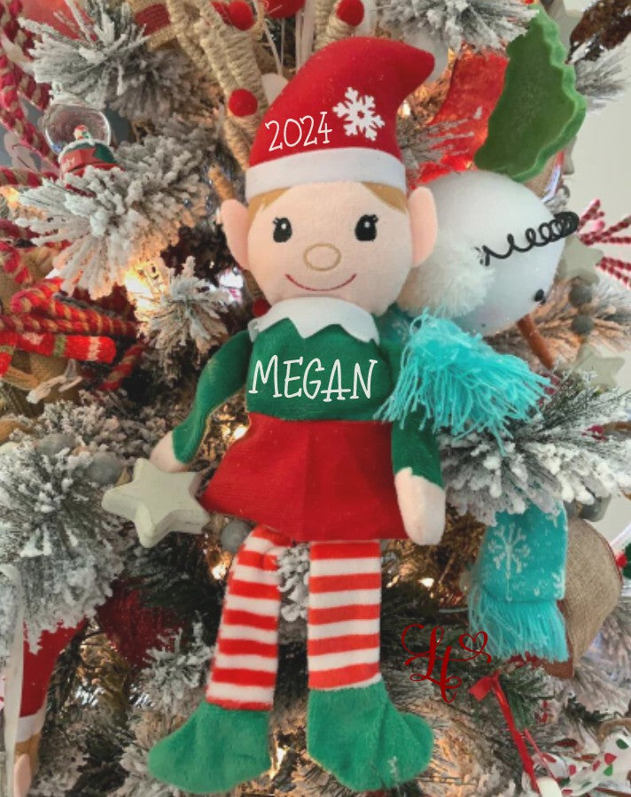 Elf doll with '2024' and 'MEGAN' text, surrounded by Christmas decorations