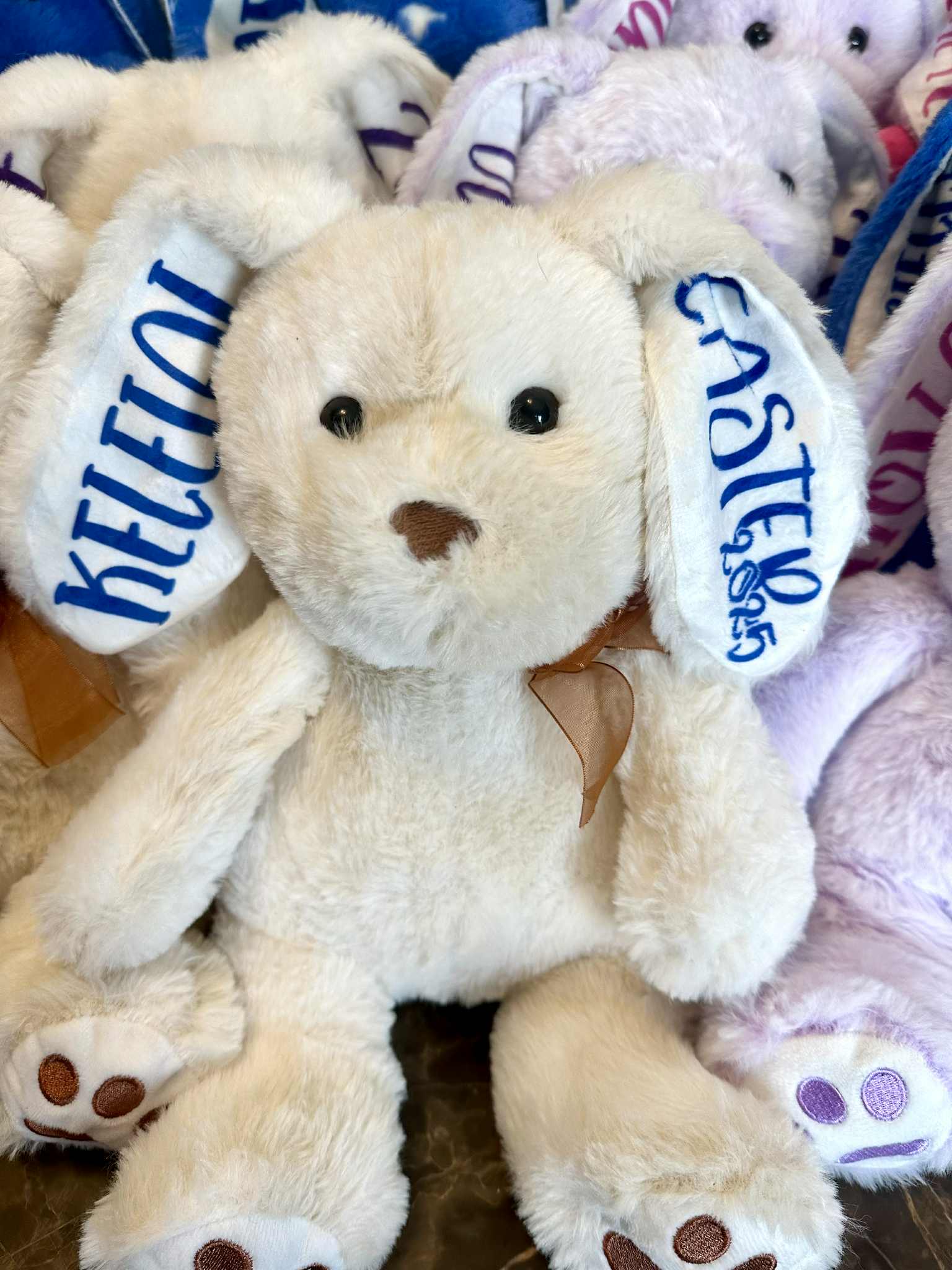 Beige stuffed bunny with 'KELLY' and 'CASTLE' tags among other plush toys.