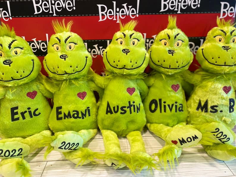 Green plush toys with personalized names on a wooden surface