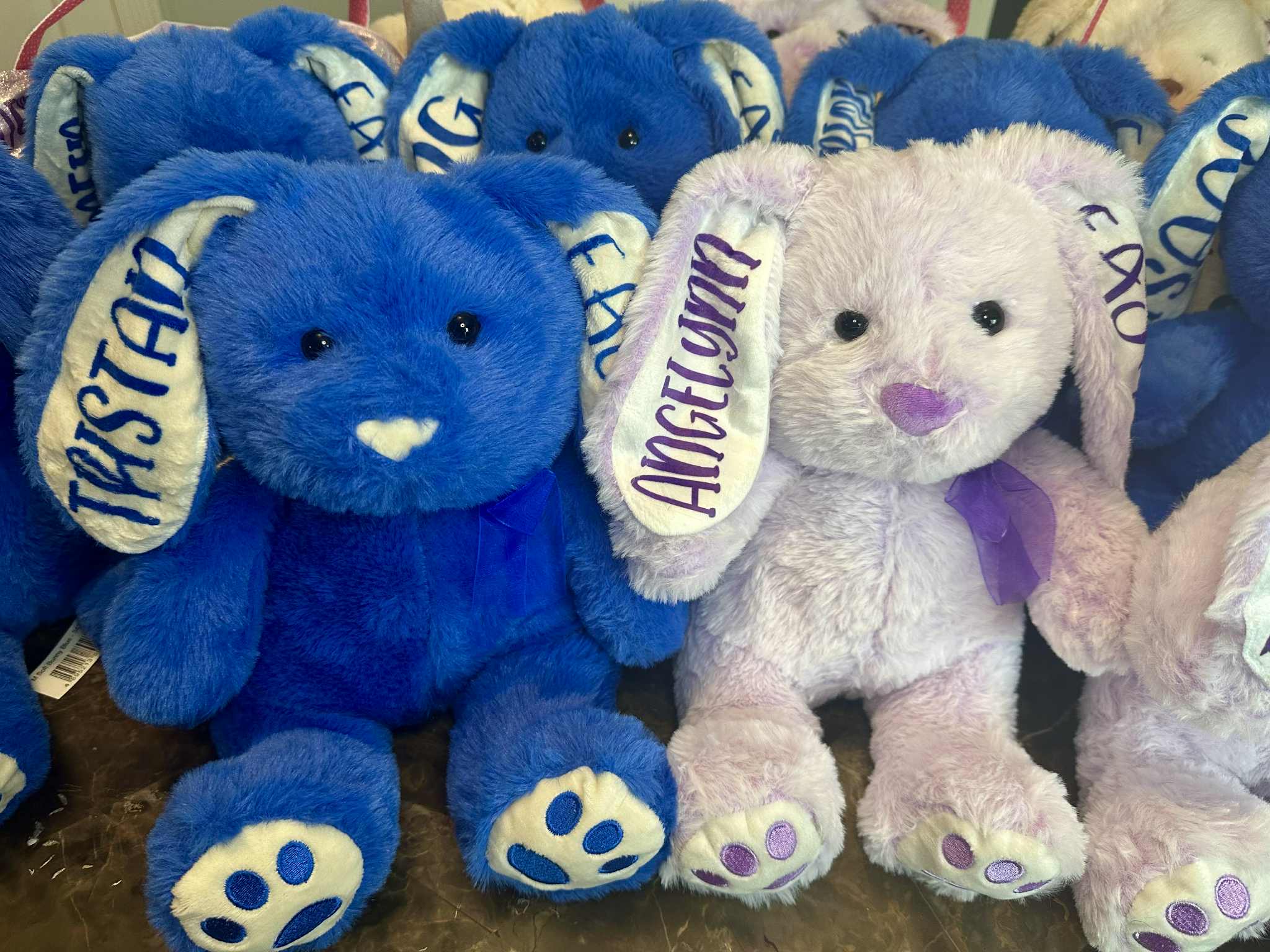 Blue and pink stuffed animals with visible branding on a dark surface