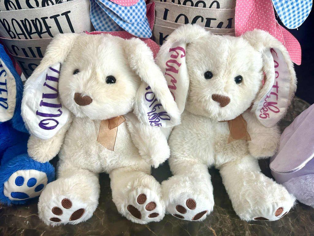 Two plush toys with name tags on a surface