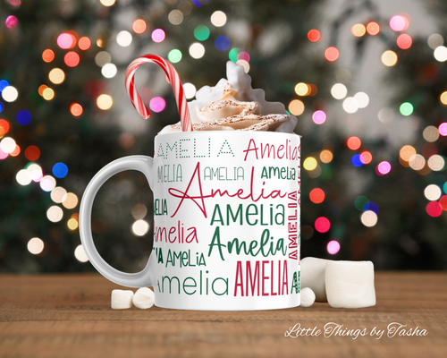 Personalized mug with whipped cream, candy cane, and 'Amelia' text against a blurred Christmas lights background.