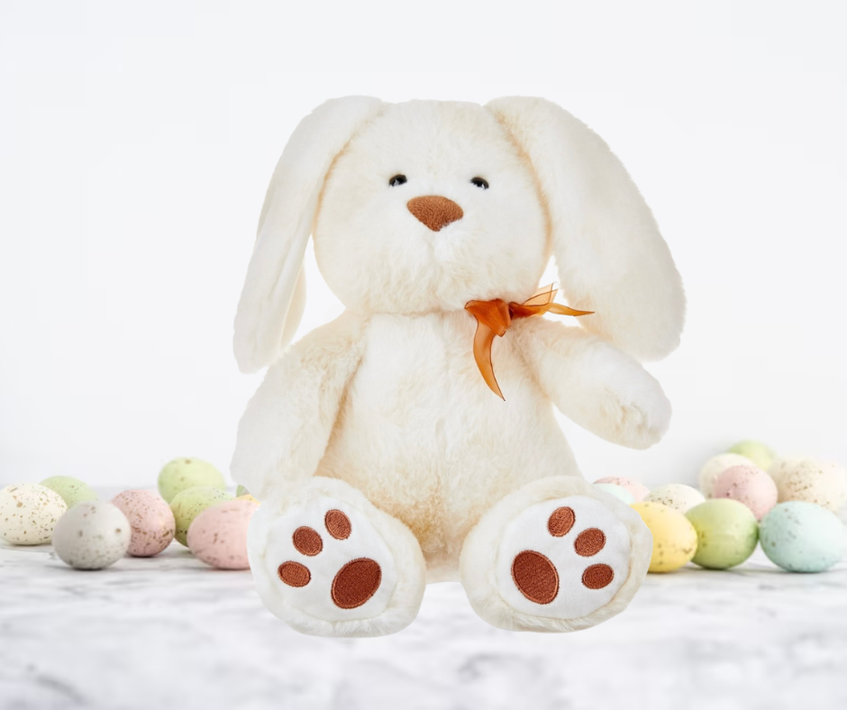 White plush bunny with brown paws and a bow tie, surrounded by colorful Easter eggs on a white background.
