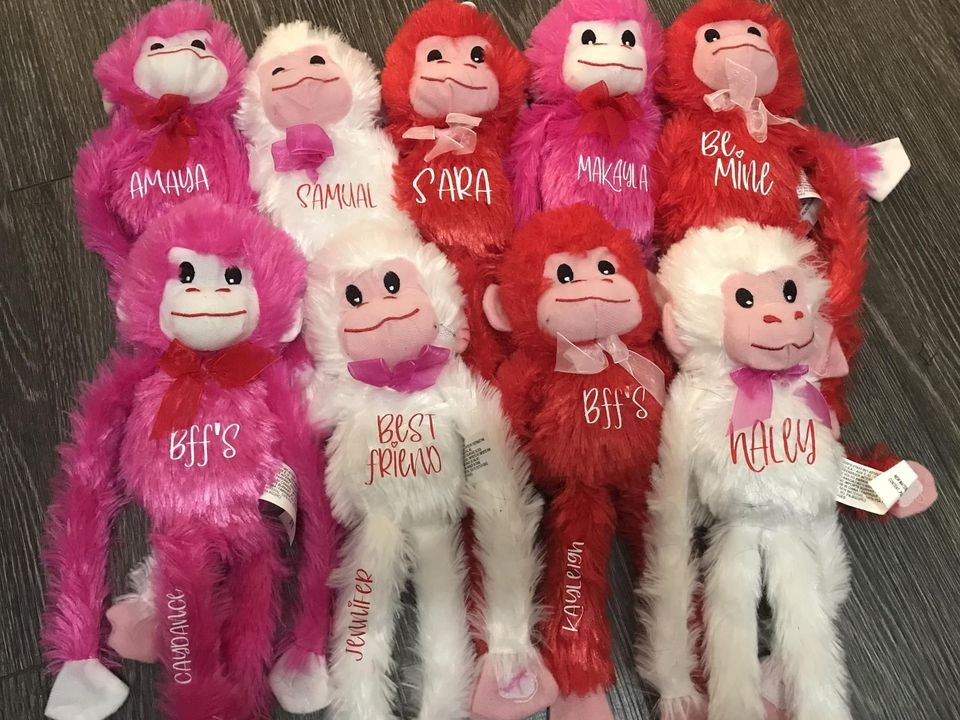 Plush monkey toys with personalized names on a wooden surface
