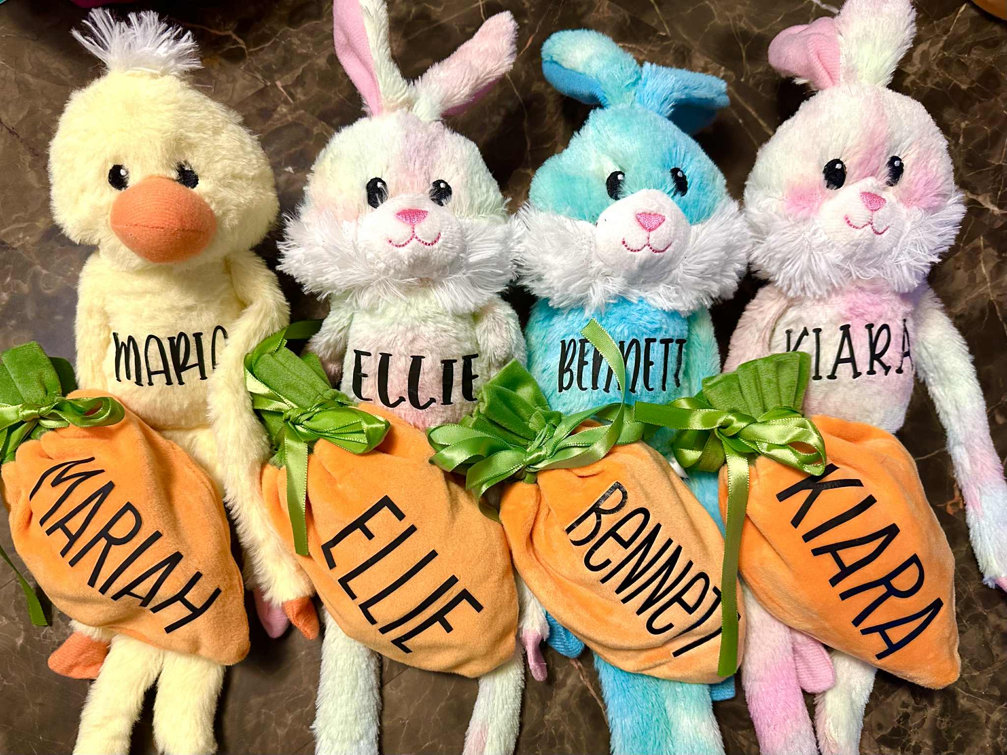 Four plush toys with name tags on a brown background